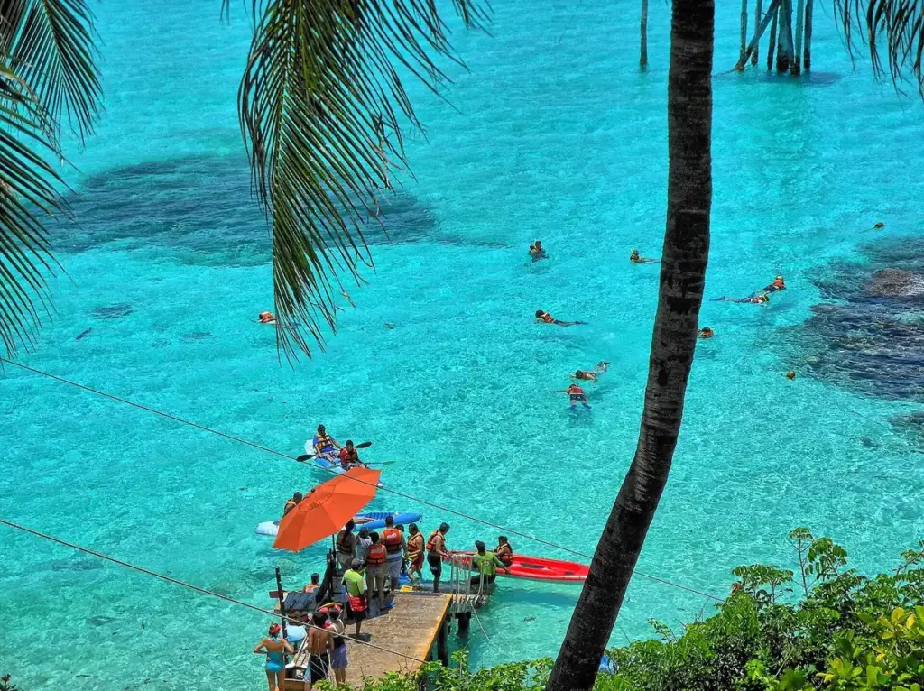 Snorkelers in turquoise water over a shallow reef beside a pier at Garrafon on Isla Mujeres, Mexico