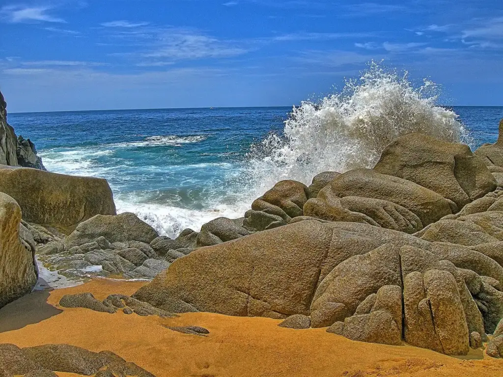 Waves breaking over granite boulders on the sand at Lovers Beach near Land's End, Los Cabos
