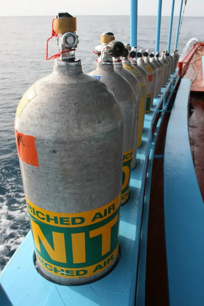 Row of scuba cylinders with green and yellow enriched air nitrox labels on the deck of a dive boat off Koh Tao, Thailand