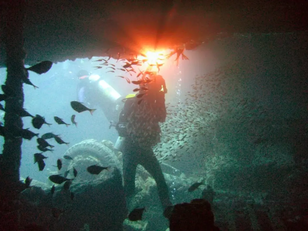 Diver with a video light filming inside the hold of the SS Thistlegorm wreck in the Red Sea