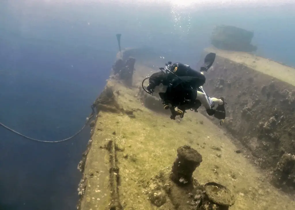 Scuba diver swimming along the deck of a shipwreck in Apra Harbor, Guam