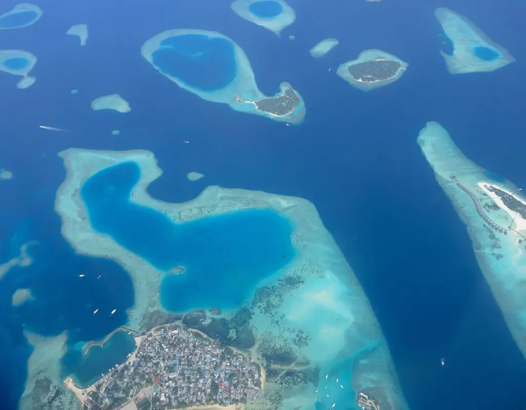 Aerial view of Guraidhoo island and the turquoise reefs and deep blue channels of South Malé Atoll, Maldives