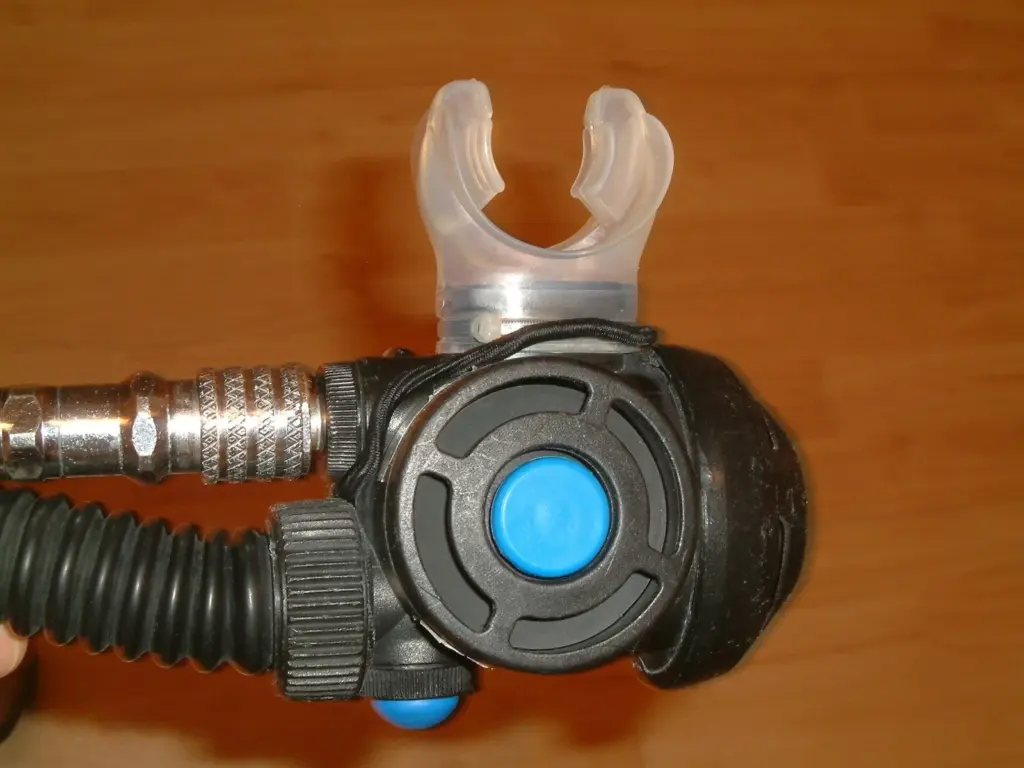 Scuba regulator second stage with mouthpiece and purge button beside a BCD inflator
