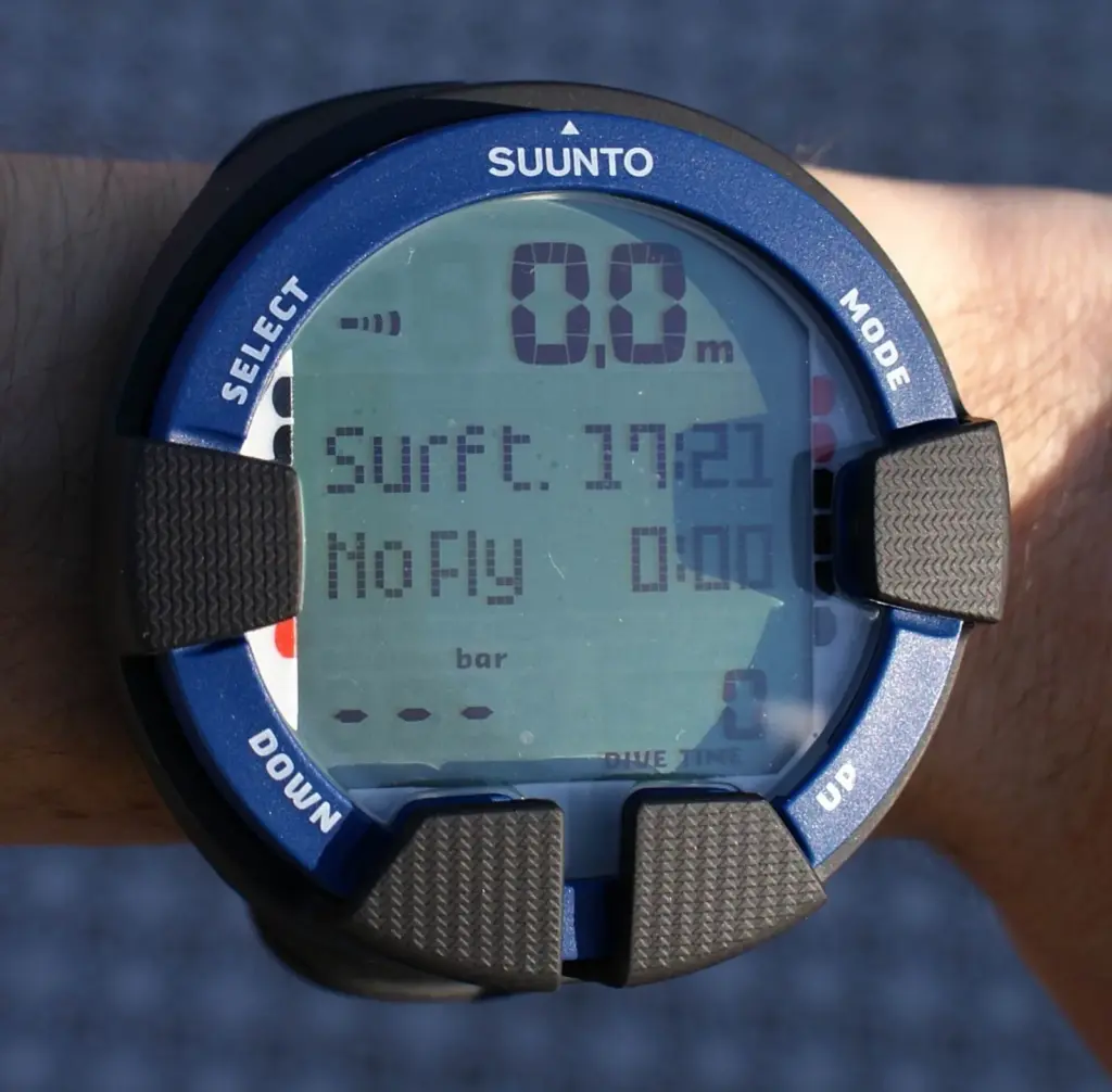 Wrist-mounted Suunto dive computer showing surface time and a no-fly counter